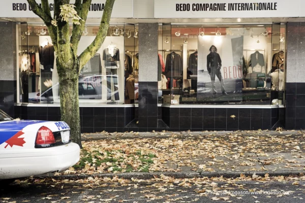 Police car in front of a shop window with leaves on the street an sidewalk