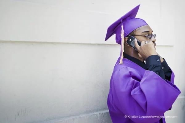 Boy graduating from school talking on a phone by a white wall in Louisiana 2006