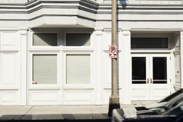 White wall with shop windows and door wit a car part in front