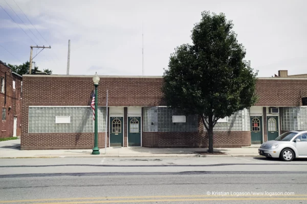 Part of a car and a tree in front of a brick building in Indiana