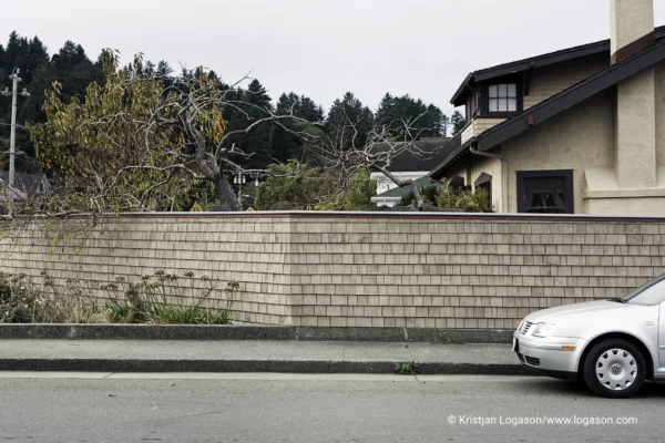 Part of a silver grey care parked infront of a brick fence in Ferndale, California