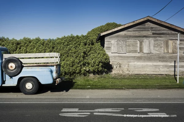Blue old pickup truck in front of a wooden building in Half moon bay, California