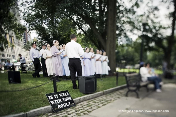 CHOIR singing in a park with a sign in front that says "is it well with your soul", Baltimore